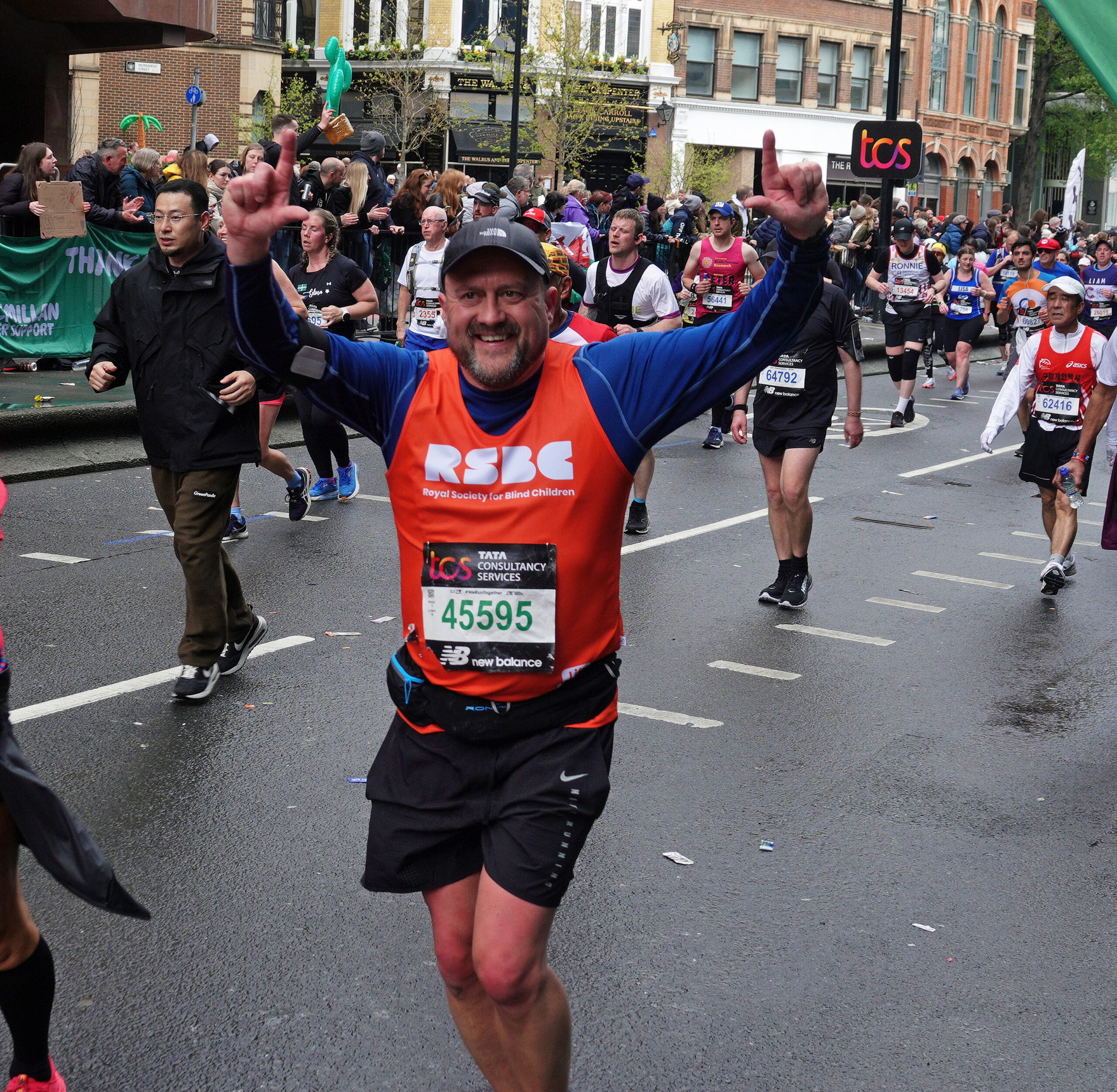 A man in the crowd wearing the RSBC orange vest and with his arms up