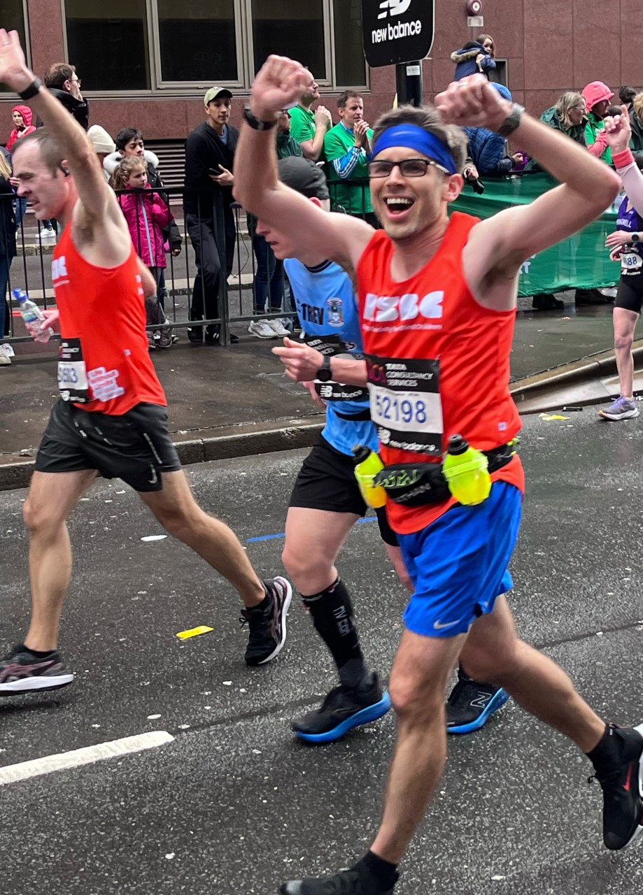 A man in the crowd wearing the RSBC orange vest and with his arms up