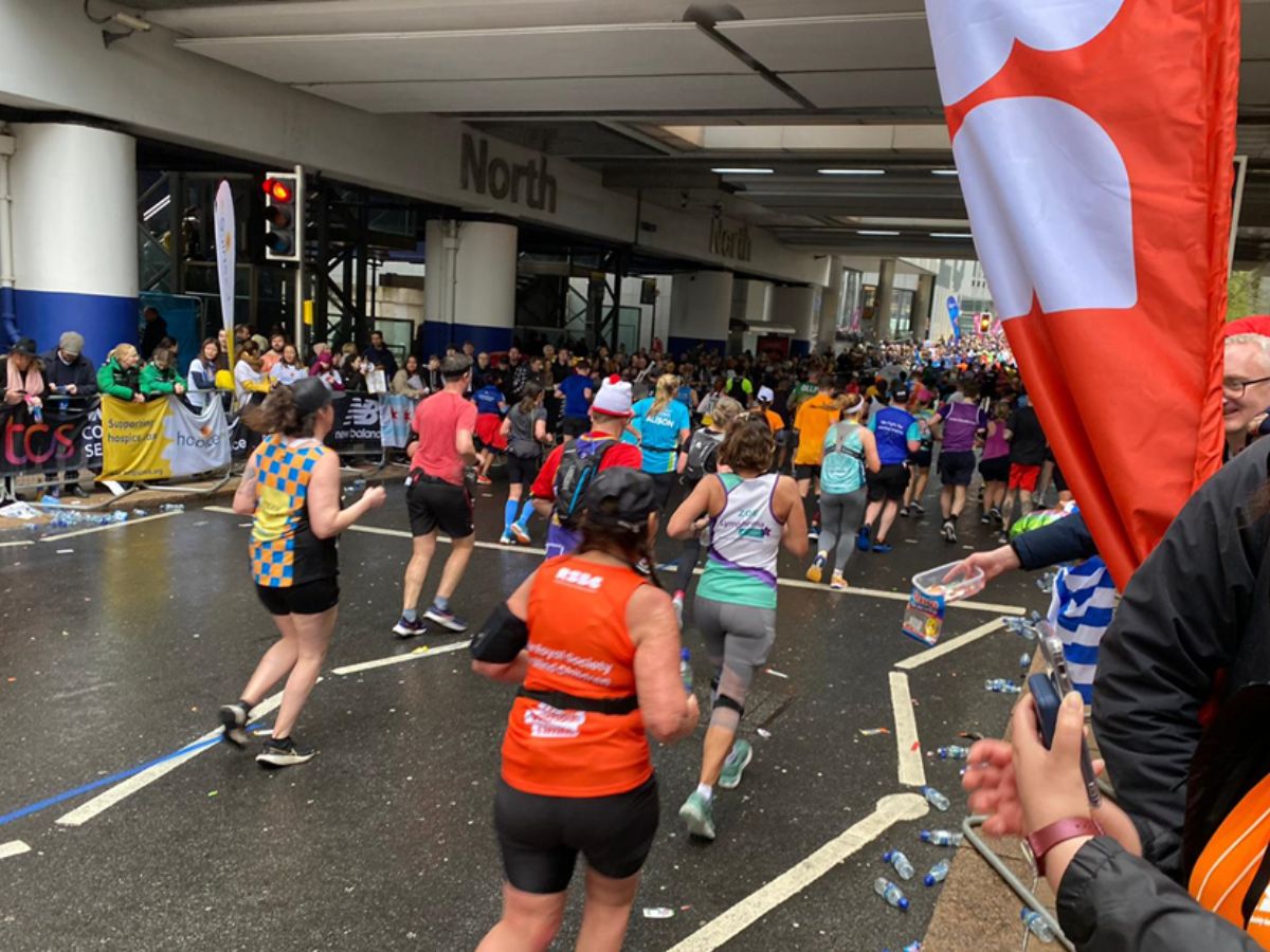 Female runner wearing the RSBC orange vest passing the RSBC cheer-point