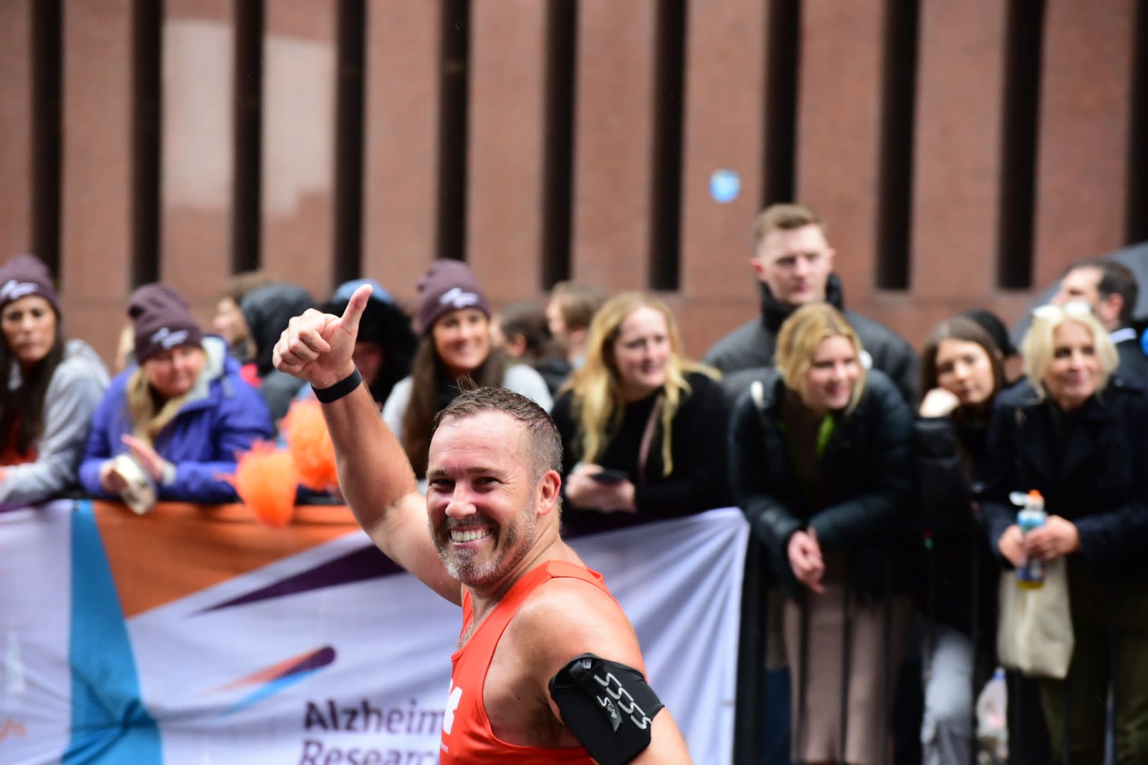 A man in the crowd wearing the RSBC orange vest and with his thum up