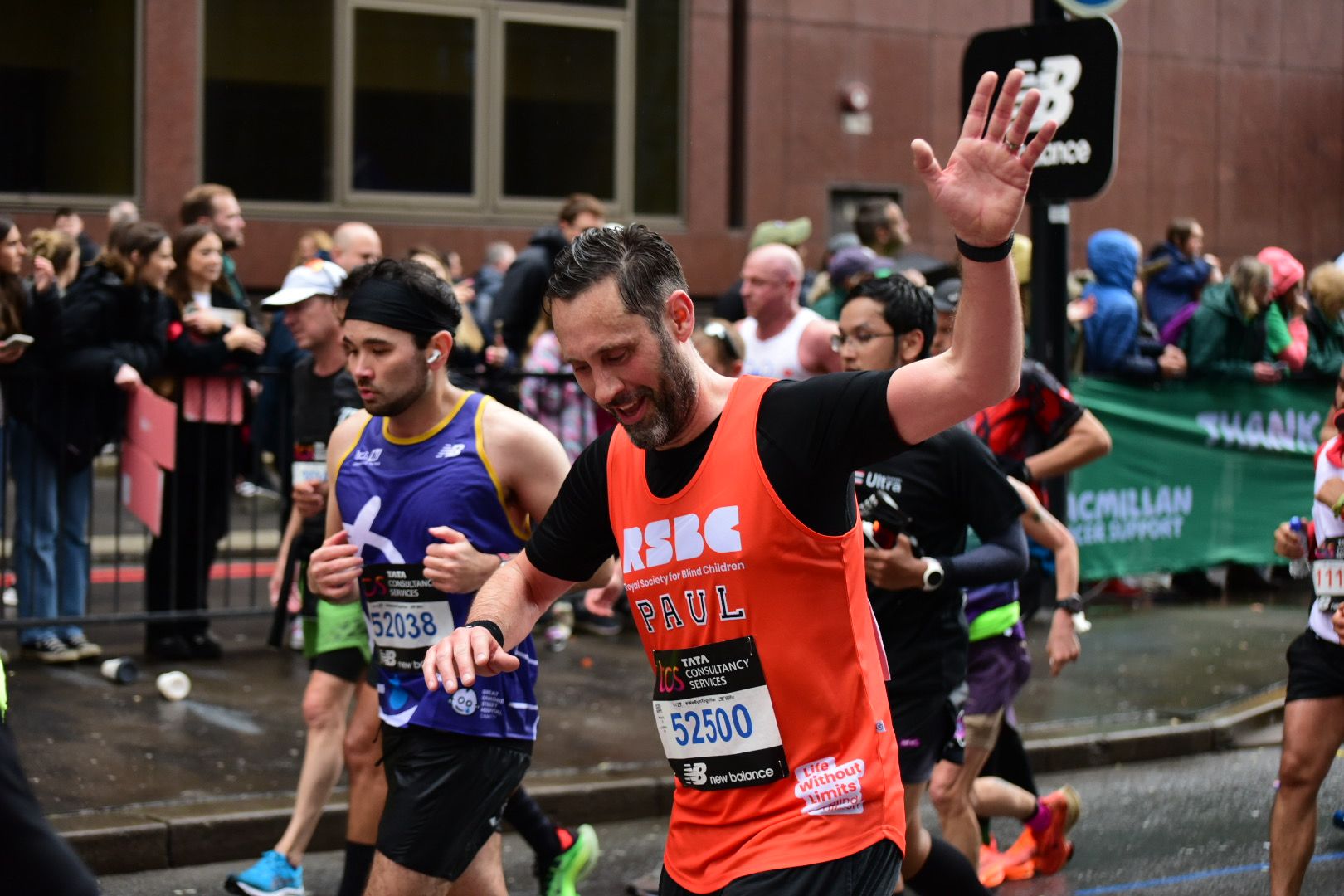 A man in the crowd wearing the RSBC orange vest and with his arms up