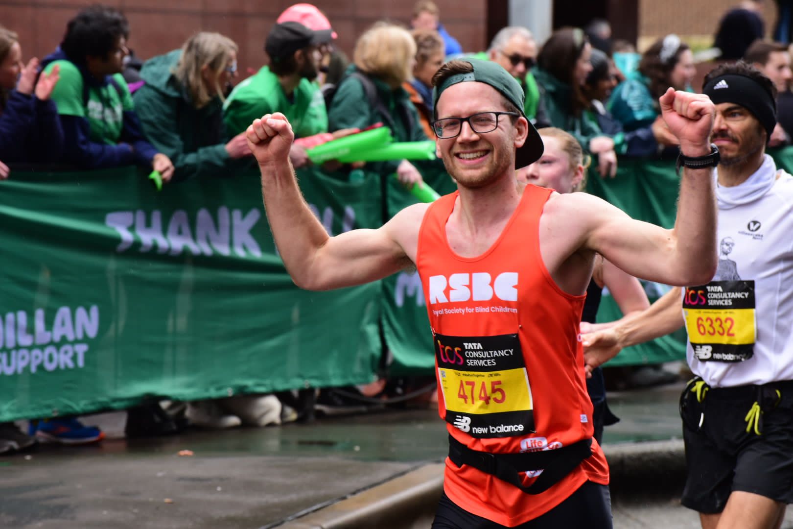 A man in the crowd wearing the RSBC orange vest and with his arms up