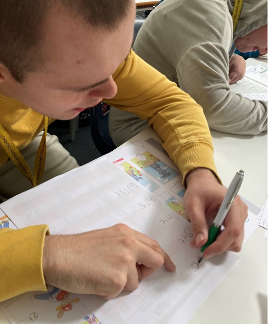 A young man writing with a pen on a piece of paper