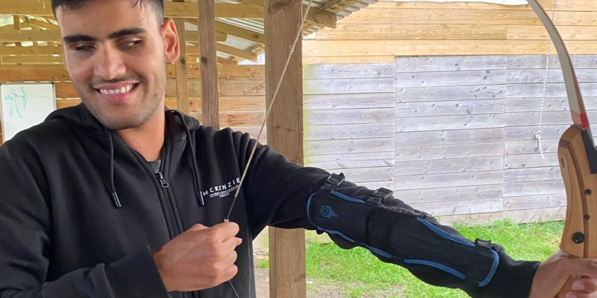 A vision impaired young man doing archery.