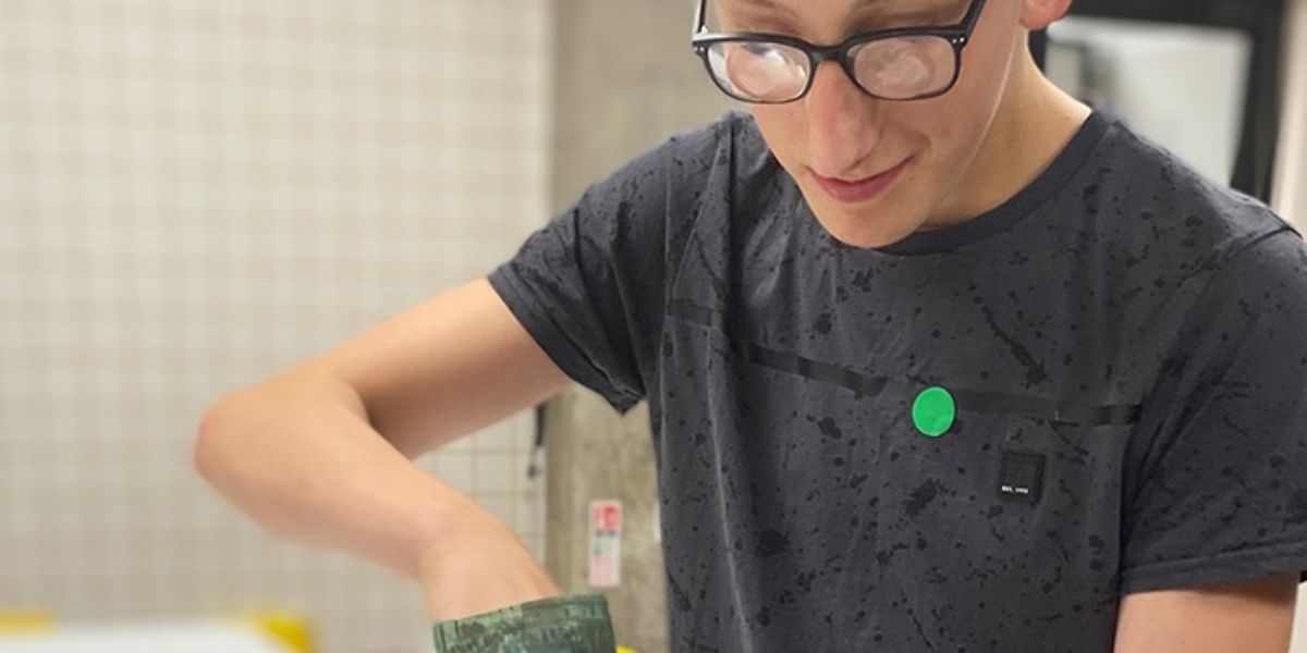 A vision impaired young man in a kitchen looking down with his hand in a bag.