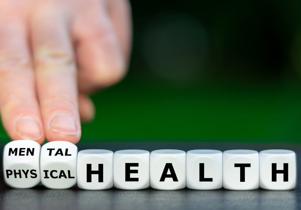 A person' fingers turn over small white blocks spelling out Mental and Physical Health