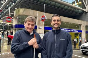 Dr Ton Pay and Celso Zuccollo are smiling and standing close together outside the entrance to the Cannon Street Underground Station in London.
